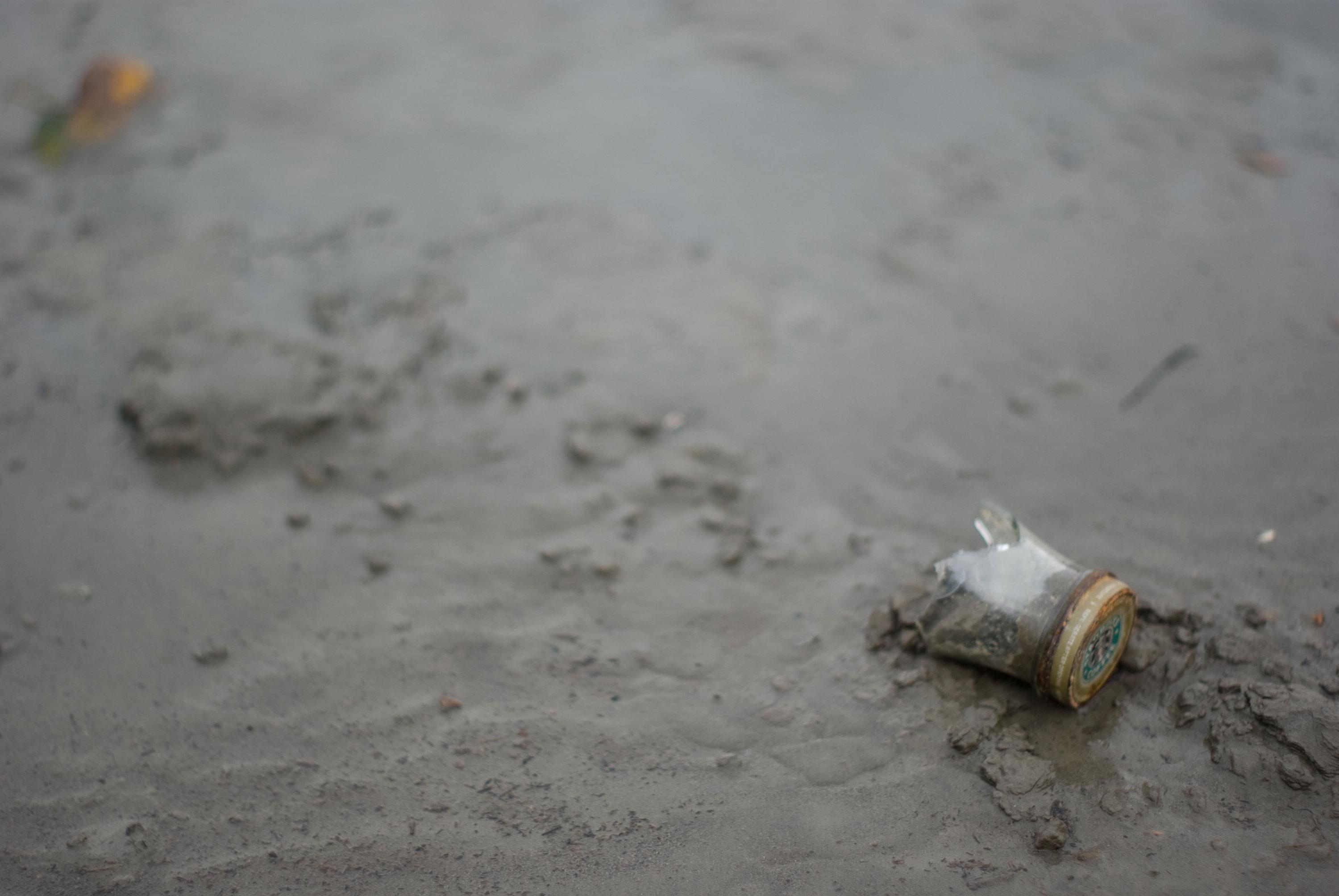 A photo of a broken starbucks bottle in the sand