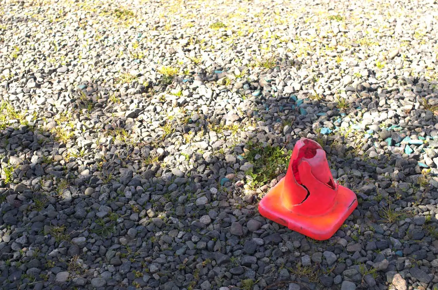 A fluorescent orange pylon on a stoney background