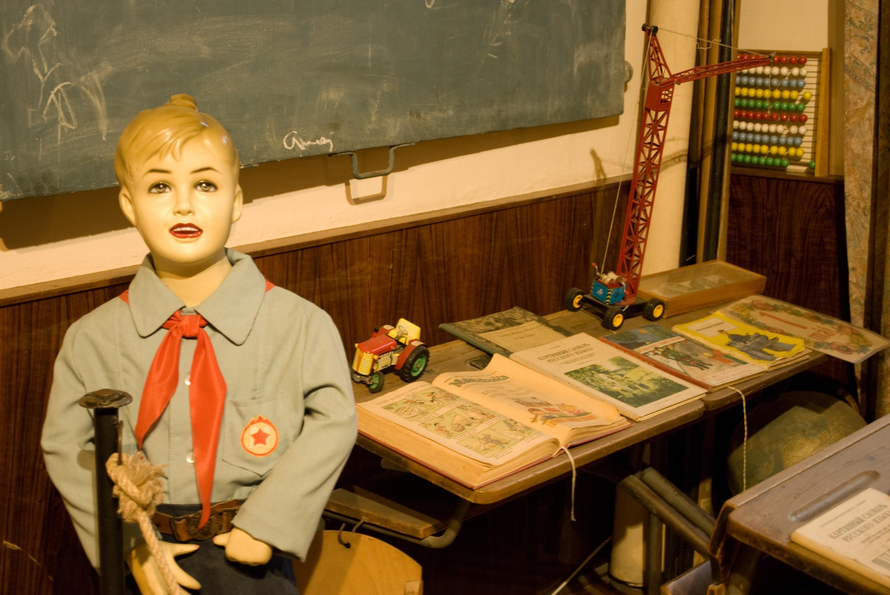 A plastic figure of a girl standing in front of a chalkboard dressed in a communist school uniform