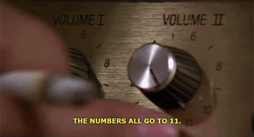 A finger gesturing to a series of amplifier knobs that are on a scale from zero to eleven